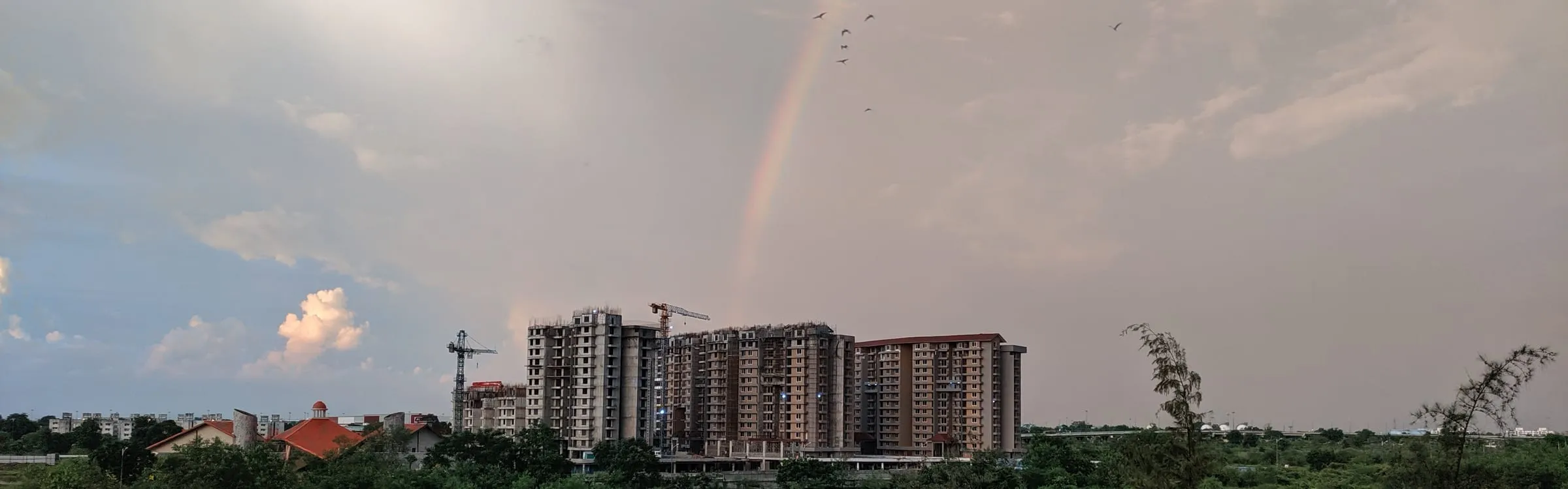 Tower blocks under construction beneath a rainbow